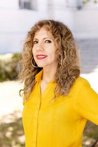 Dr. Hada Sanchez wearing yellow blouse with greenery in background