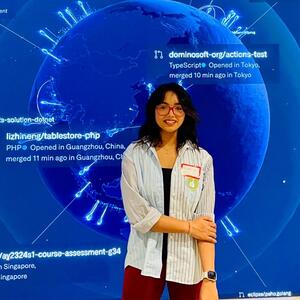 Aastha Singh standing in front of blue background with a large blue earth with text.
