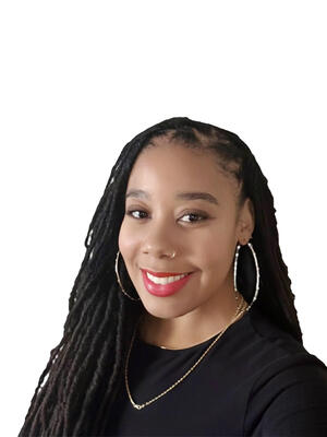 Headshot of Dr. Honey Walrond smiling wearing a black shirt in front of a white background.