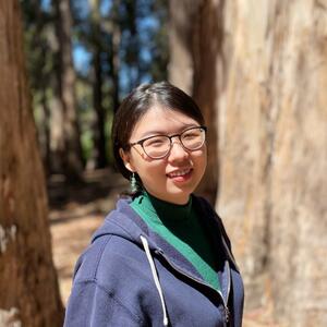 Dr. Xiao Liu headshot wearing blue jacket in front of trees in background