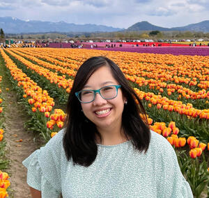 Dr. Jaqueline Phan standing in front of colorful flowers in background.