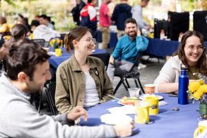 Postdocs sitting around a table enjoying coffee and pastries in outdoor patio.