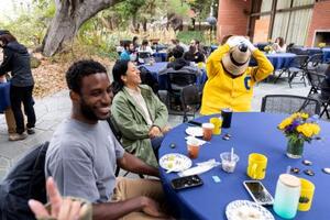 Postdocs sitting around a table with Oski the bear covering his eyes.