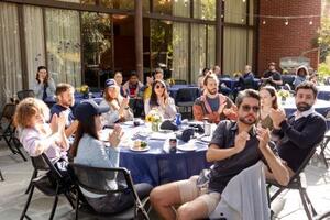 Postdocs sitting around table clapping and chatting at PostdocFest event.