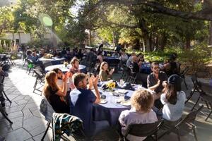 Postdocs sitting around table and chatting at PostdocFest event in shade