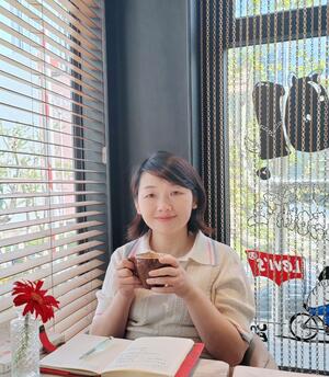 Yun Chen sitting in a cafe holding a mug.