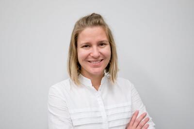 Dr. Jenni Shearston headshot photo wearing white top and crossing her arms.