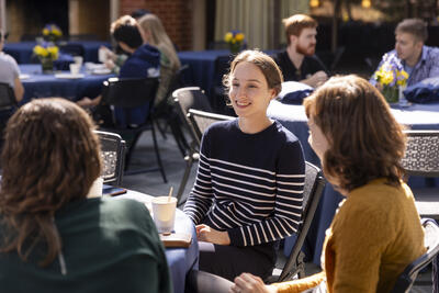 Postdocs sitting around a table enjoying coffee and pastries in outdoor patio.