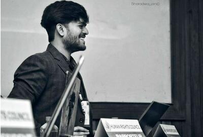 black and white photo of Vaivab Das in profile sitting at a panel table with a table card that reads Human Rights Council.